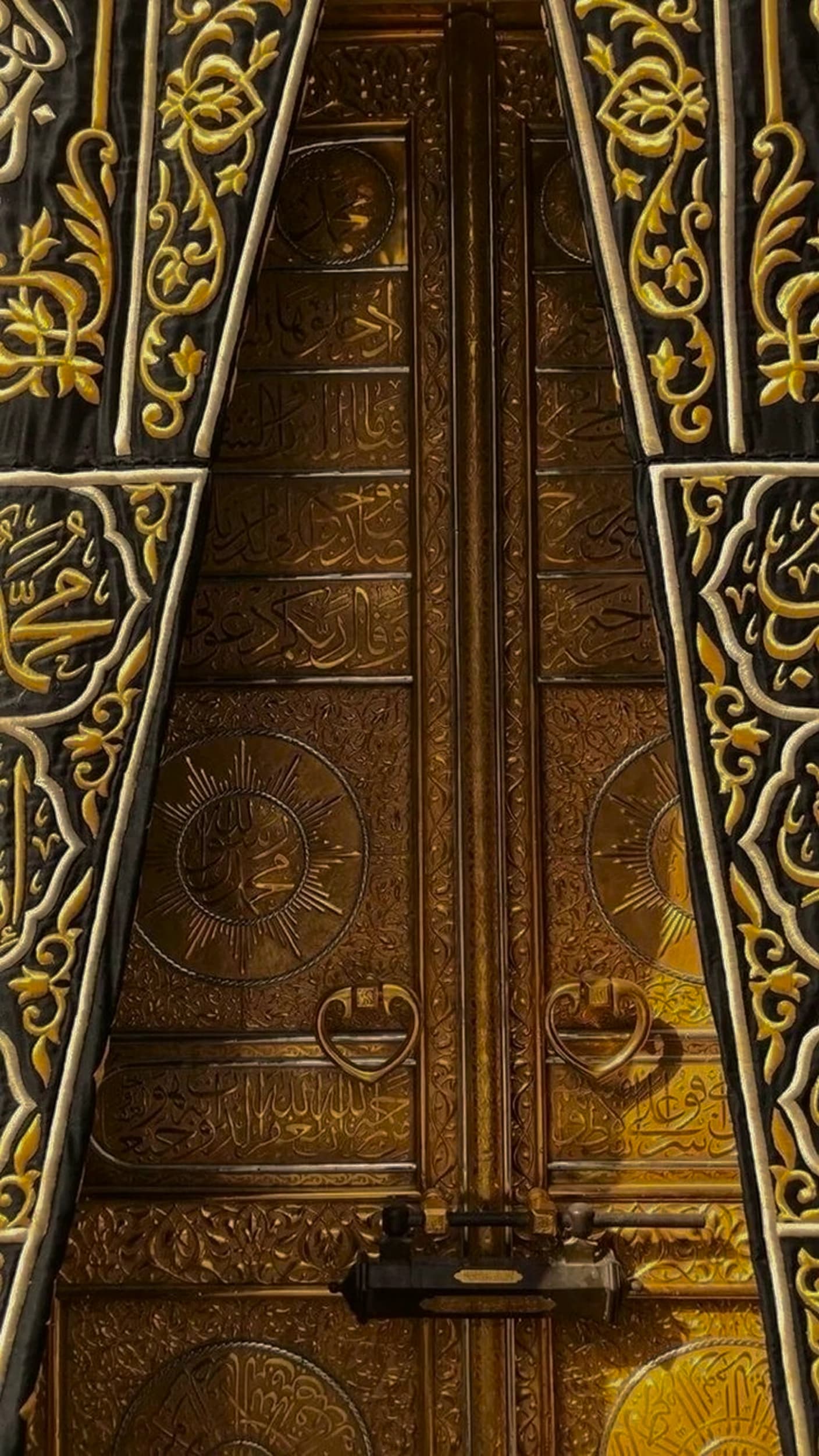 Close-up of the Kaaba's golden door, its leaves covered in raised Arabic calligraphy and framed by the embroidered curtain.
