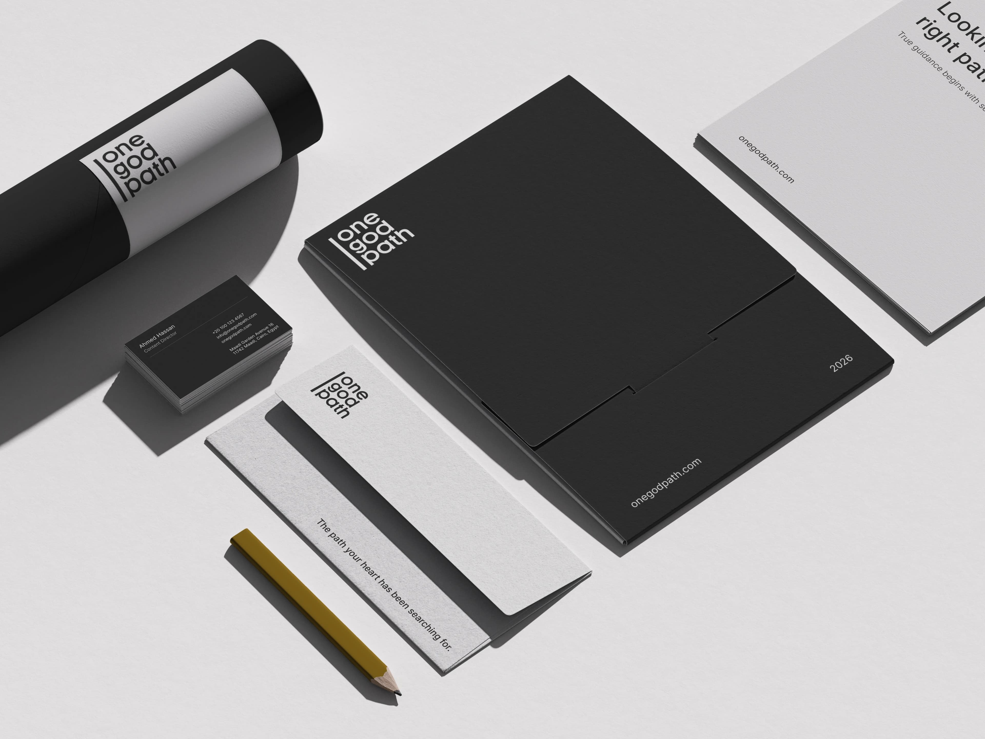 Branded stationery is arranged on light grey: a poster tube, business cards, a folder, letterhead, a booklet and a gold pencil.