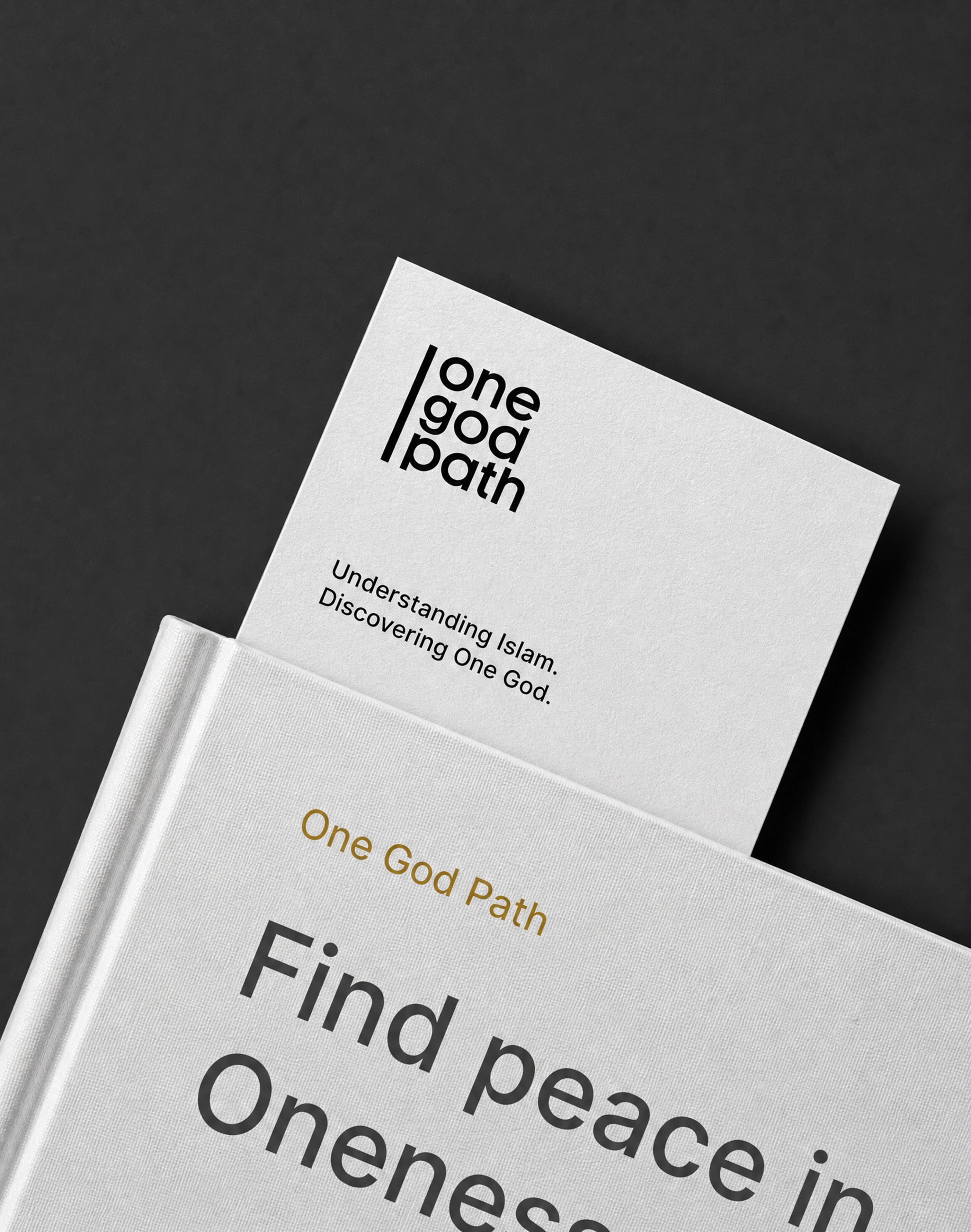 A stacked white booklet and card rest on a dark textured surface.