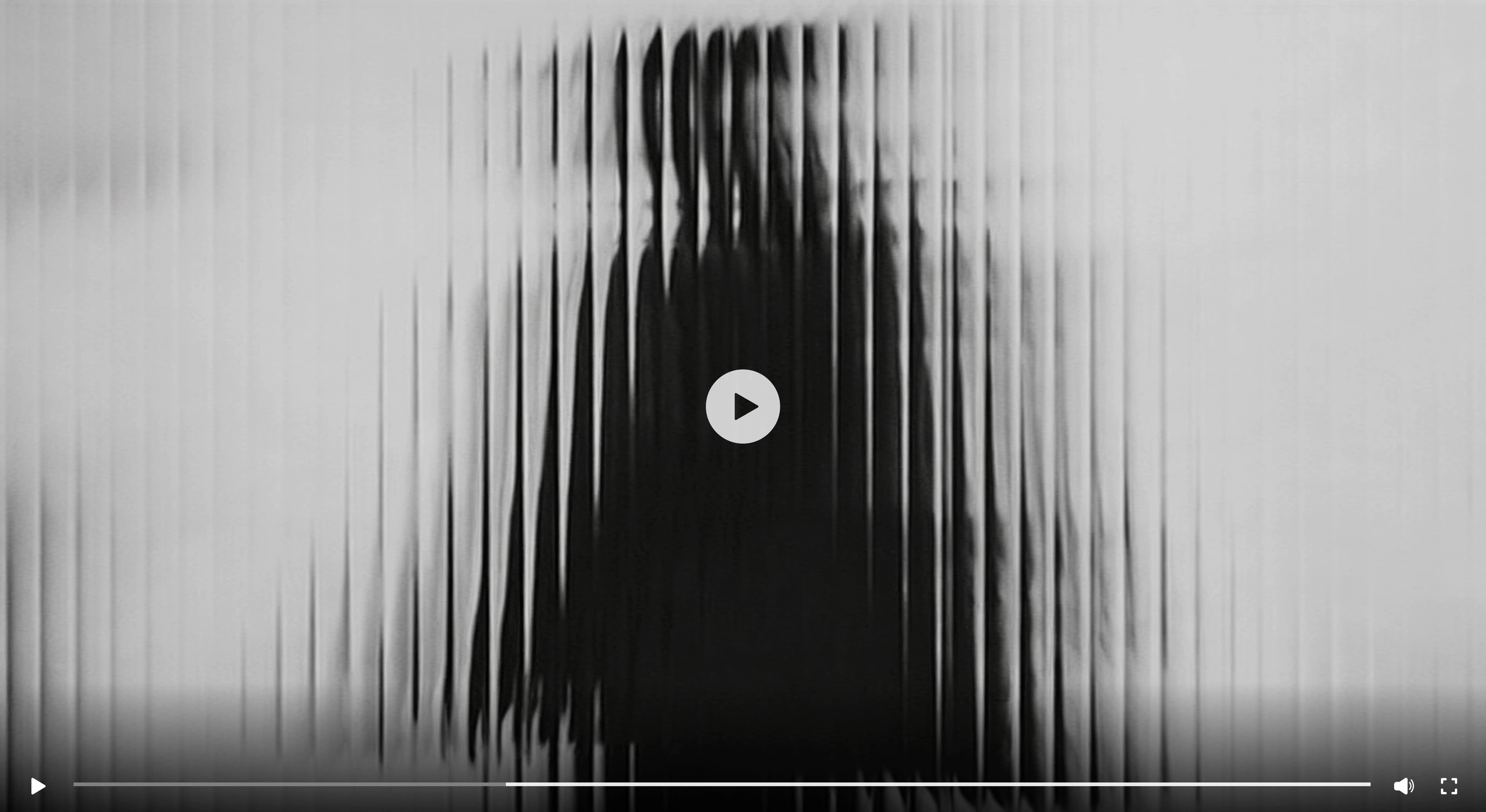 A grainy black and white still from the Saudi Formation Partners brand film, long vertical motion-blur streaks running across the frame behind a circular play button and a video transport bar.