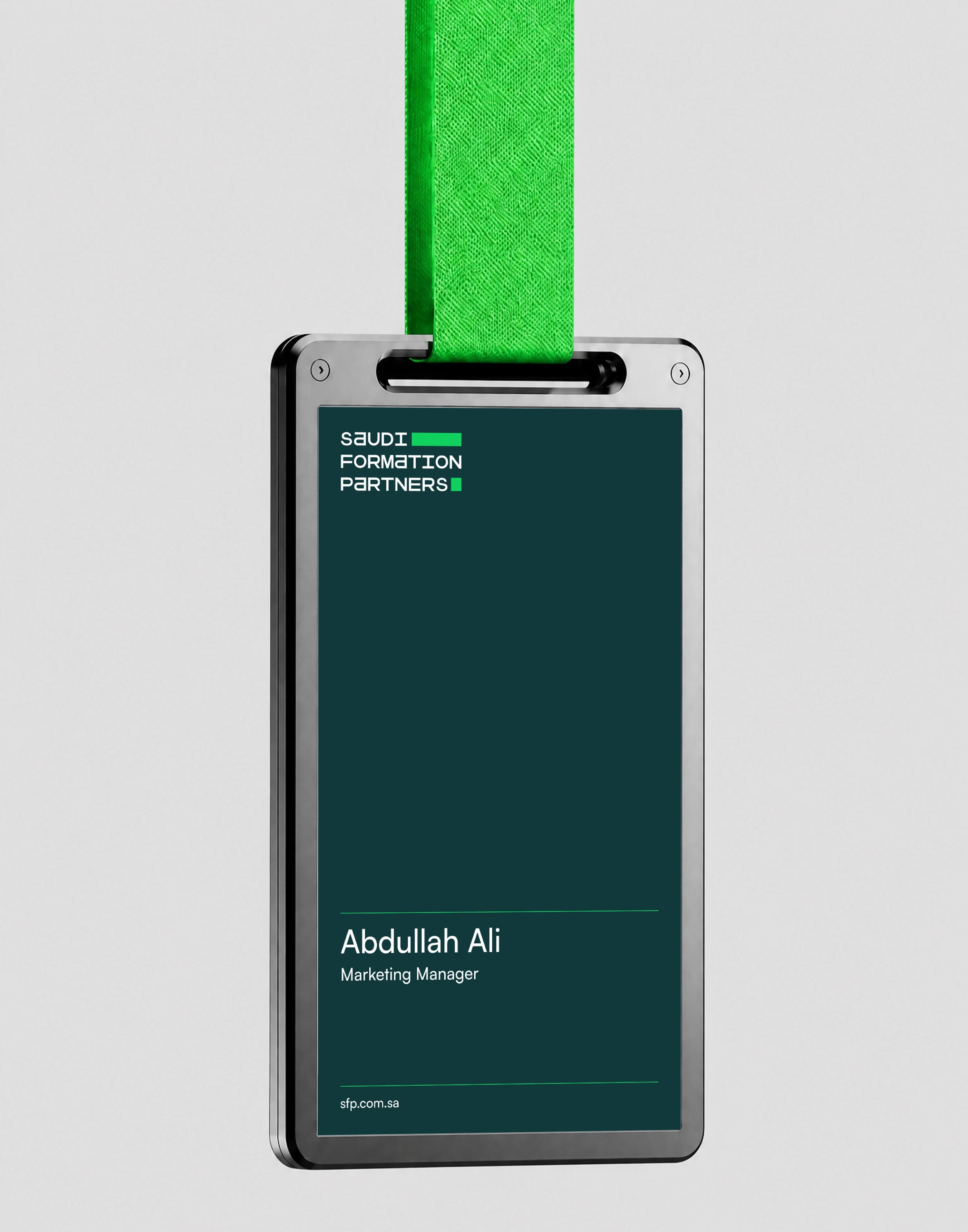 An employee ID badge hanging from a malachite green lanyard, its dark teal card carrying the Saudi Formation Partners wordmark above a name block reading Abdullah Ali, Marketing Manager, and the website address.
